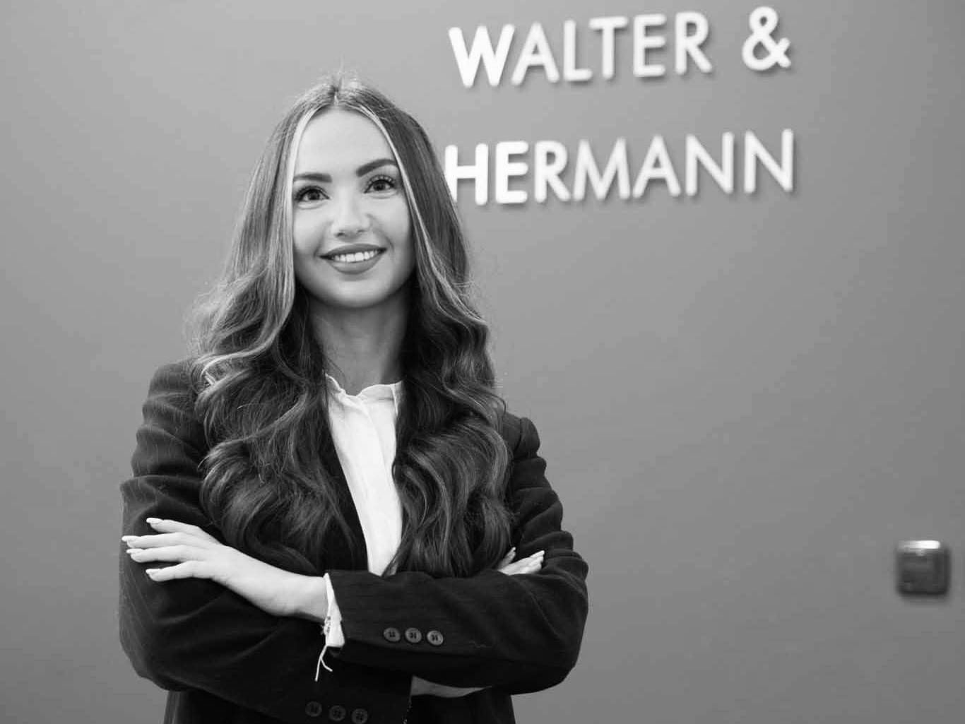 Selbstbewusste Frau in Businesskleidung vor Firmenlogo an der Wand