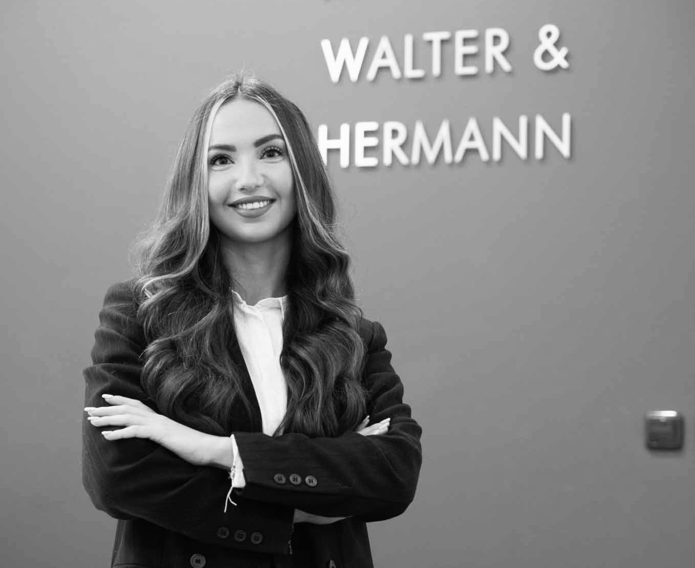 Selbstbewusste Frau in Businesskleidung vor Firmenlogo an der Wand