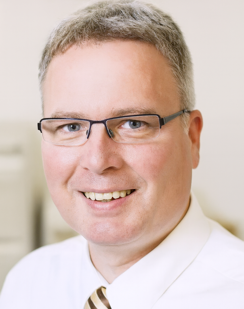 Lächelnder Mann mit Brille, weißes Hemd und gestreiftem Krawatte.