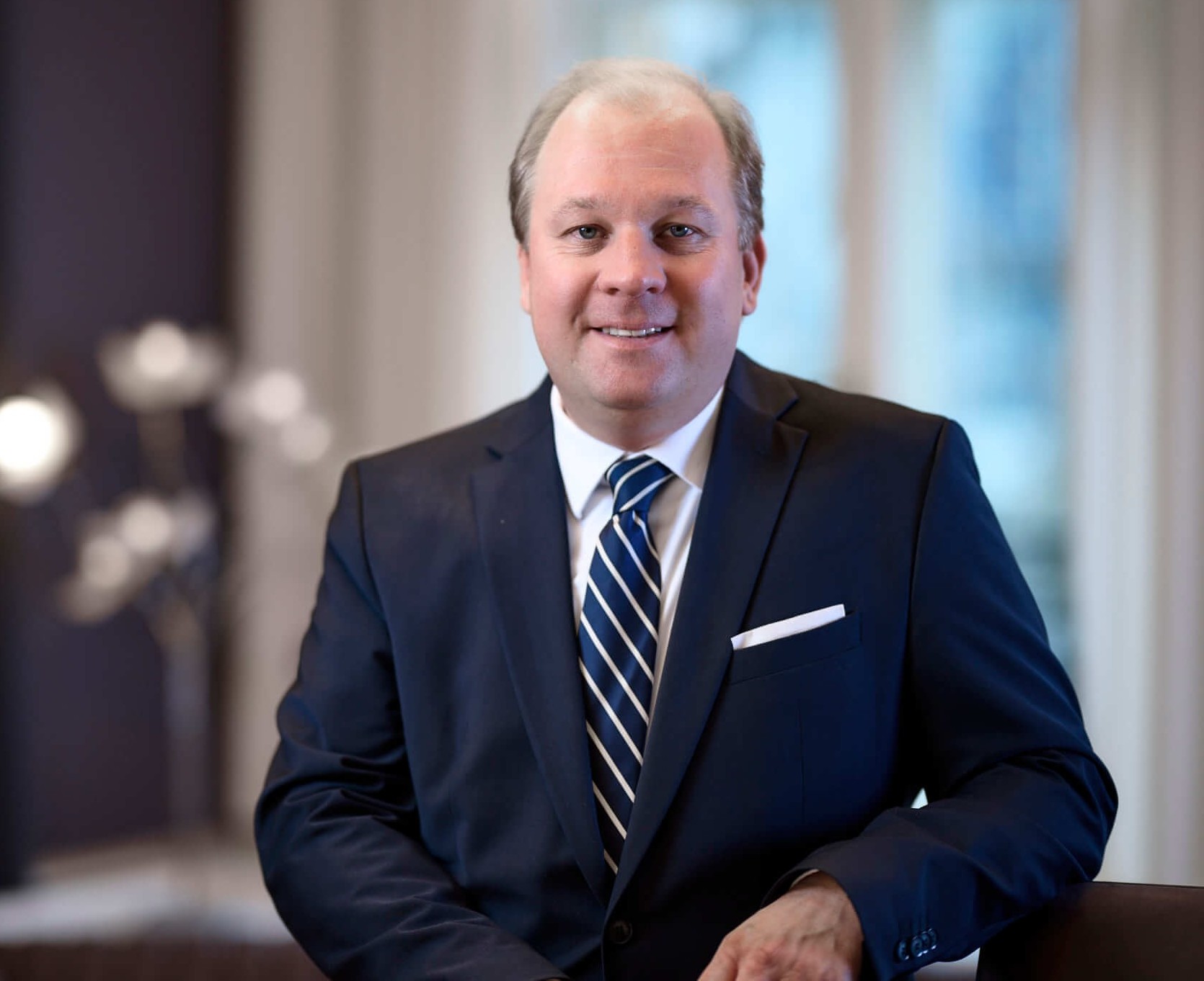 Mann in Anzug mit Krawatte, lächelnd, im Büro.