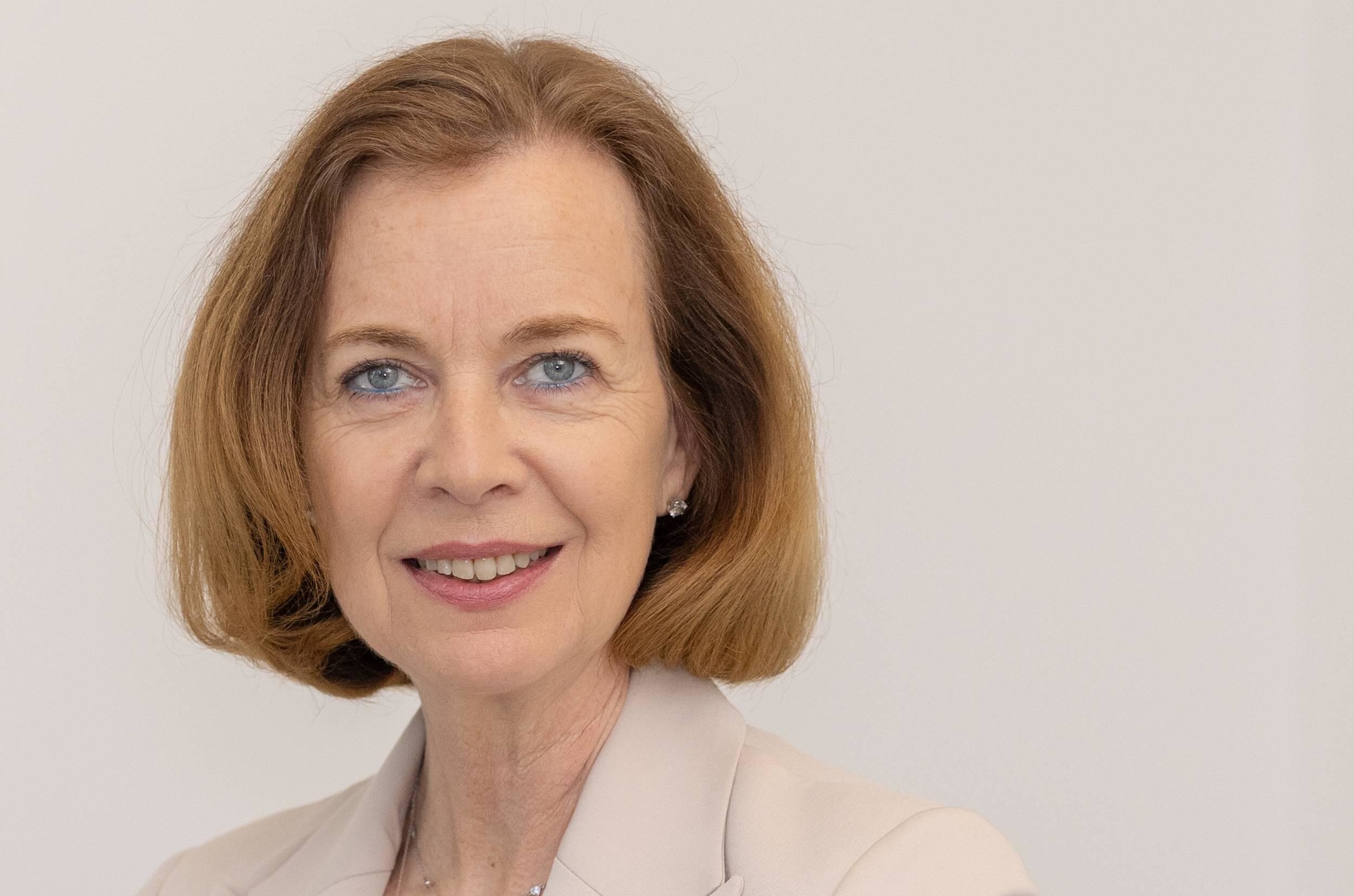 Eine Frau sitzt an einem Tisch vor einem weißen Hintergrund mit einem Schild, auf dem "DAS RECHT" steht.