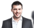 Ein Mann in formeller Kleidung vor einer Gruppe von Menschen, mit Firmenlogo im Hintergrund.
