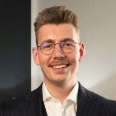 Lächelnder Mann in Anzug vor einem Bürohintergrund.