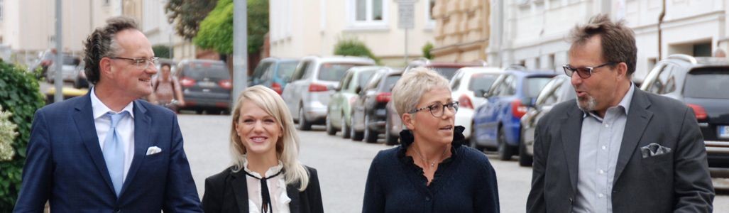 Vier Menschen, die auf einer Straße spazieren gehen und miteinander sprechen.