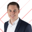 Porträt eines lächelnden Mannes in Businesskleidung vor einem schwarzen Hintergrund mit roten Linienmustern.