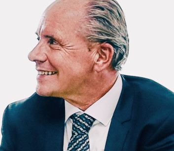 Lächelnder Mann in Anzug und Krawatte, seitlich betrachtet.