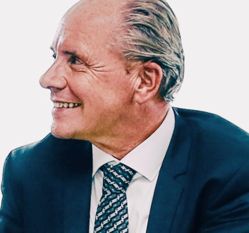 Lächelnder Mann in Anzug und Krawatte, seitlich betrachtet.