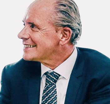 Lächelnder Mann in Anzug und Krawatte, seitlich betrachtet.