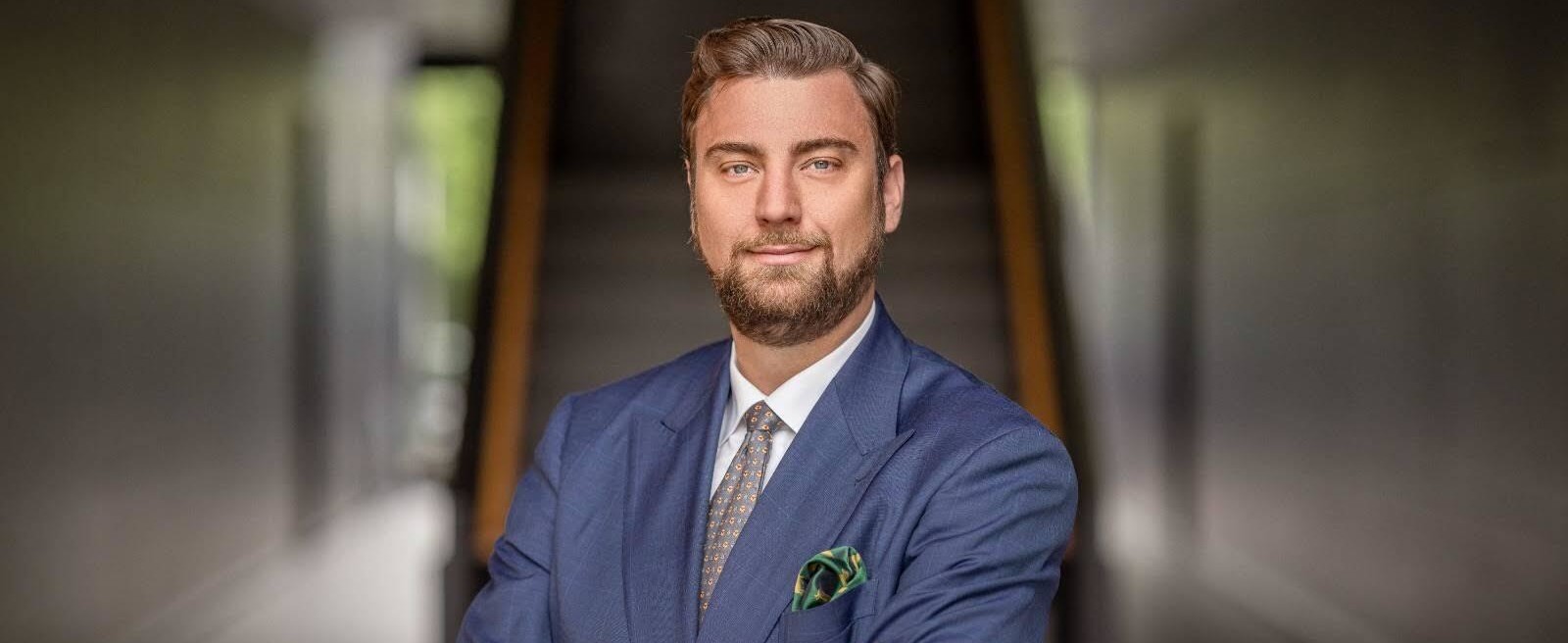 Geschäftsmann in Anzug mit verschränkten Armen vor einer Treppe.