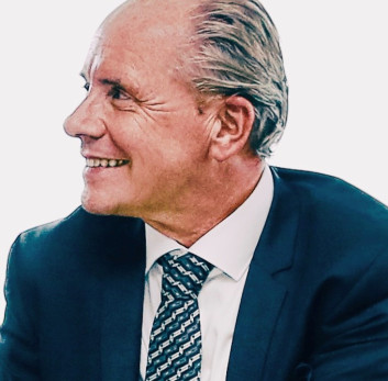 Lächelnder Mann in Anzug und Krawatte, seitlich betrachtet.