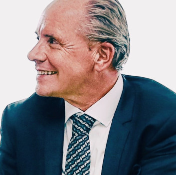 Lächelnder Mann in Anzug und Krawatte, seitlich betrachtet.