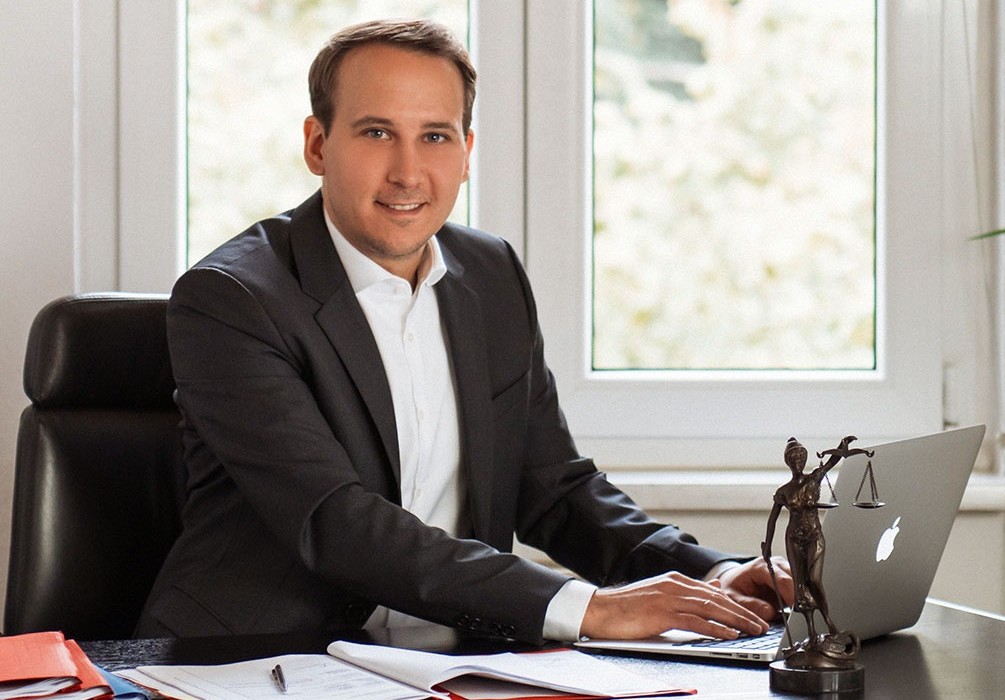 Geschäftsmann sitzt an seinem Schreibtisch im Büro, arbeitet am Laptop.