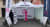Werbestand von Printmedia mit T-Shirt, Schirm und Informationsmaterial auf einer Straße.