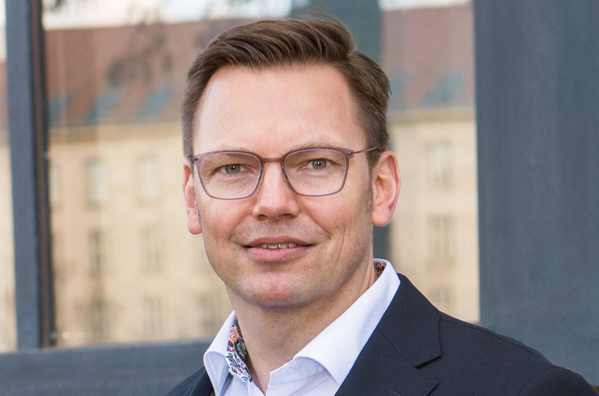Geschäftsmann in formeller Kleidung vor einem Gebäude mit Fenstern.