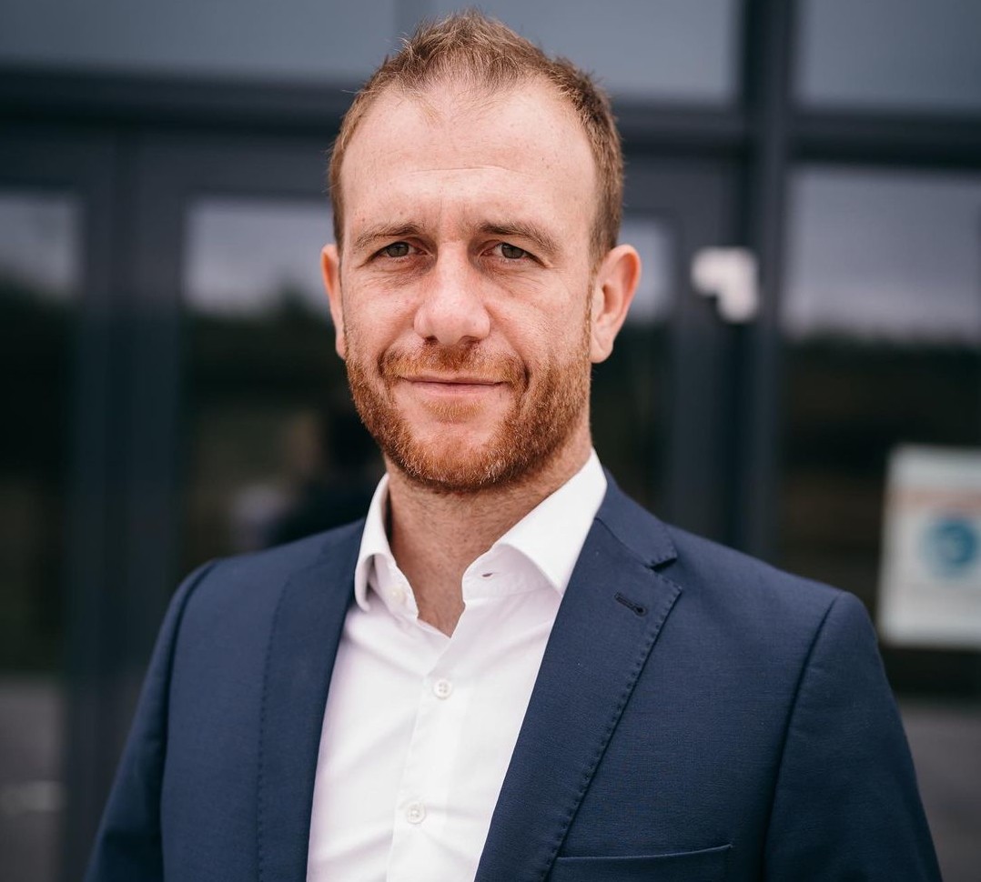 Mann in formeller Kleidung vor einem modernen Gebäude.