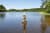 Steinmännchen im Wasser am Ufer eines Sees mit Bäumen im Hintergrund