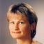 Das Bild zeigt eine Frau mit dunklen, kurzen Haaren und einem freundlichen Ausdruck.