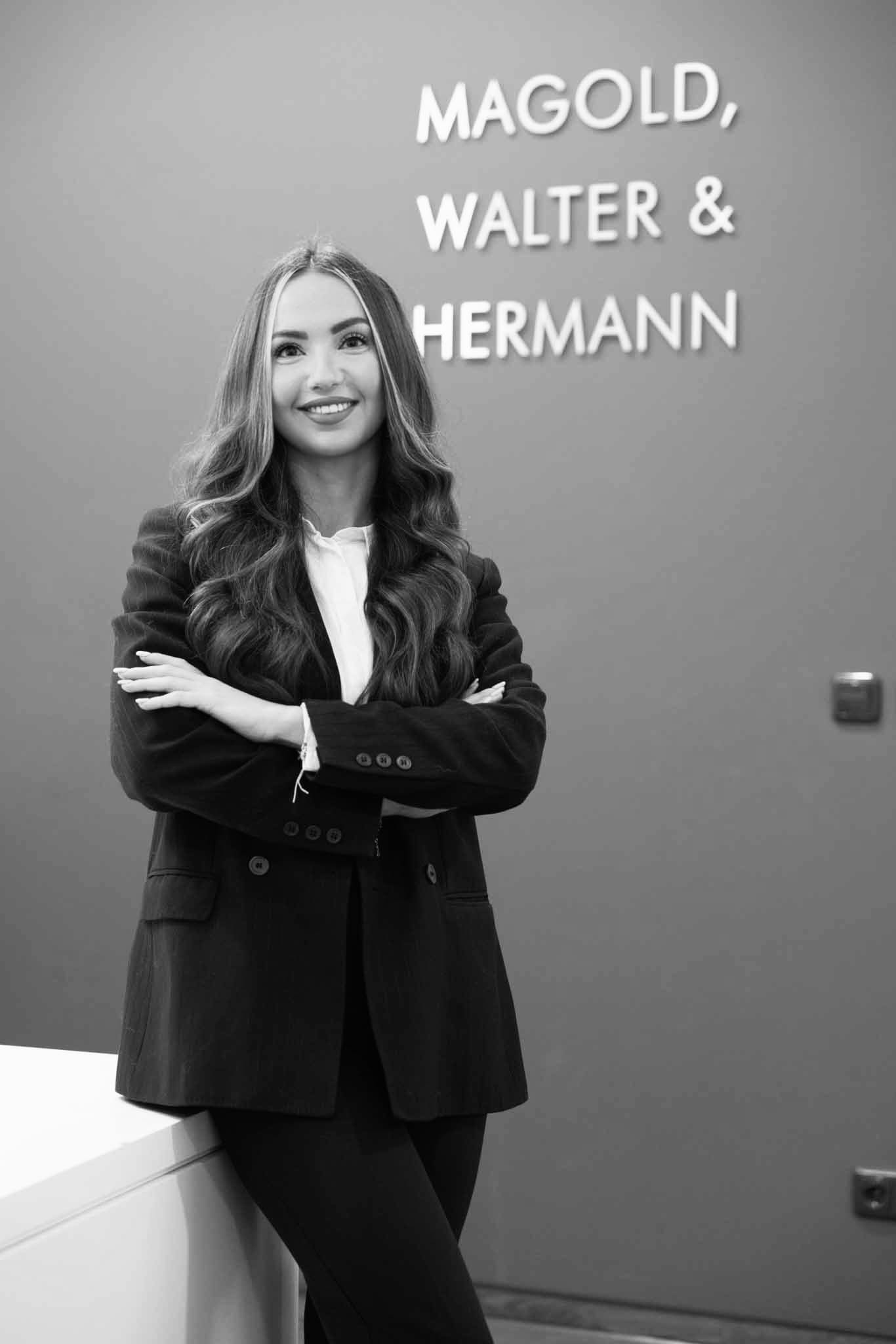 Selbstbewusste Frau in Businesskleidung vor Firmenlogo an der Wand