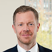 Porträt eines Mannes in formeller Kleidung vor hellem Hintergrund