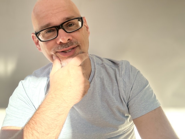 Mann mit Brille, der nachdenklich die Hand am Kinn hält.
