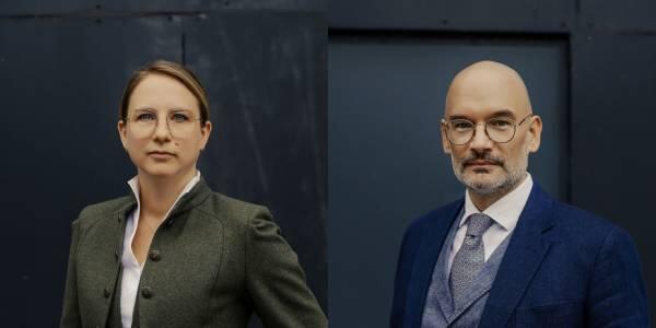 Zwei professionell gekleidete Personen vor dunklem Hintergrund, eine Frau und ein Mann.