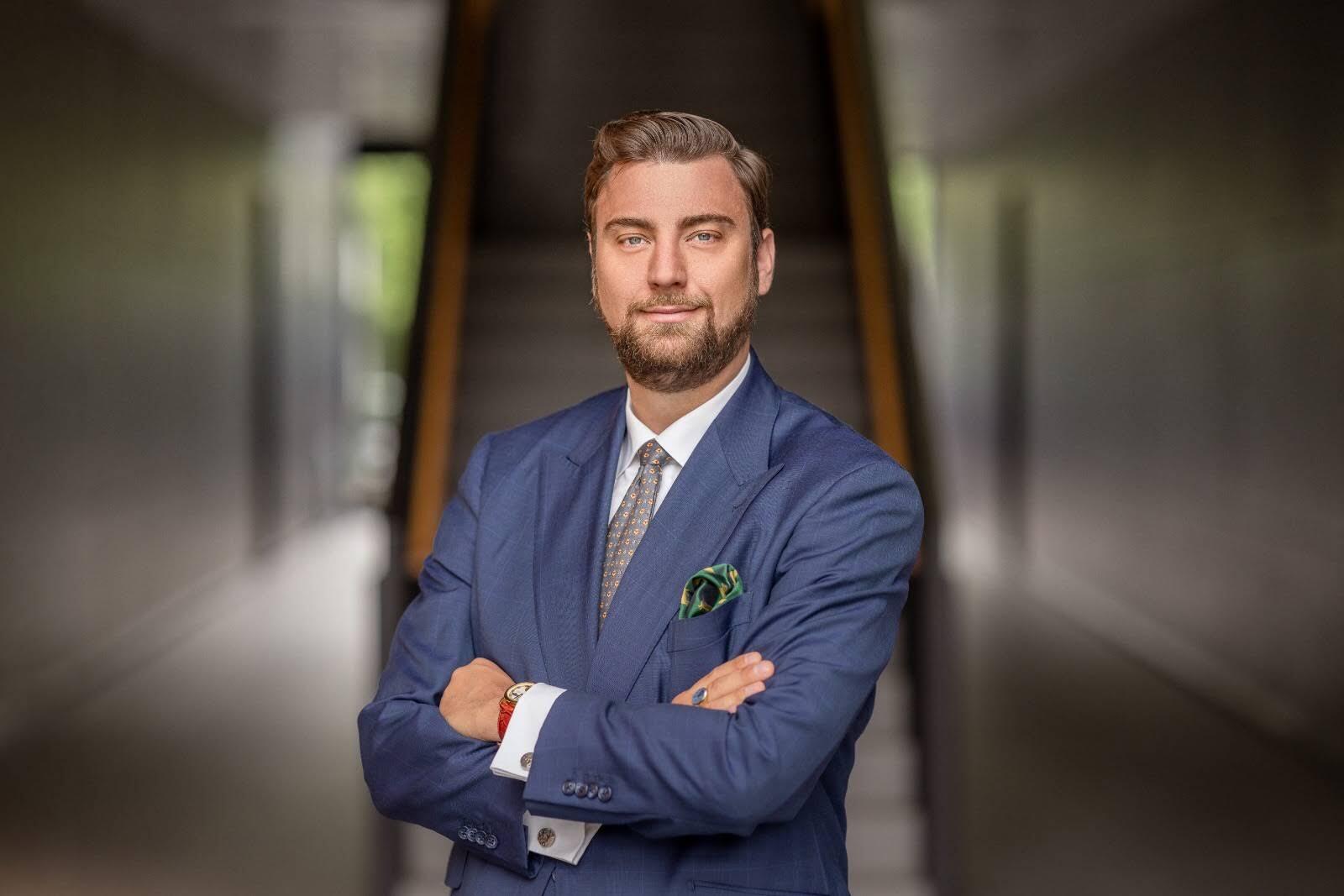 Geschäftsmann in Anzug mit verschränkten Armen vor einer Treppe.
