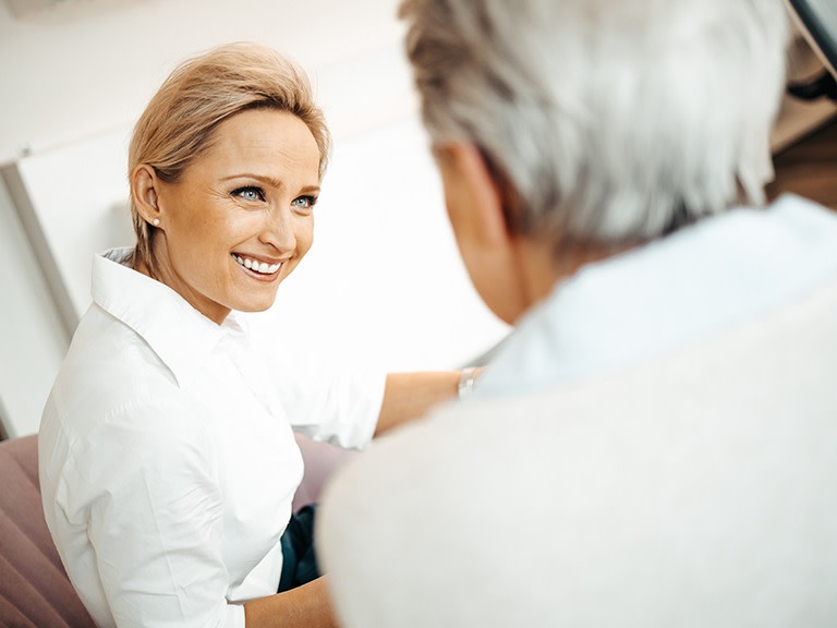 Eine Frau lächelt freundlich während eines Gesprächs mit einem älteren Mann.