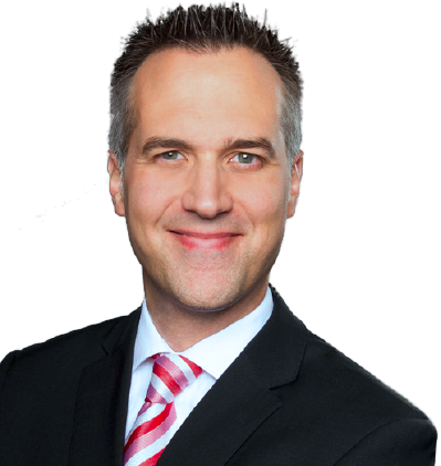 Ein Mann in formeller Kleidung mit dunklem Anzug, weißem Hemd und roter gestreifter Krawatte, lächelnd.