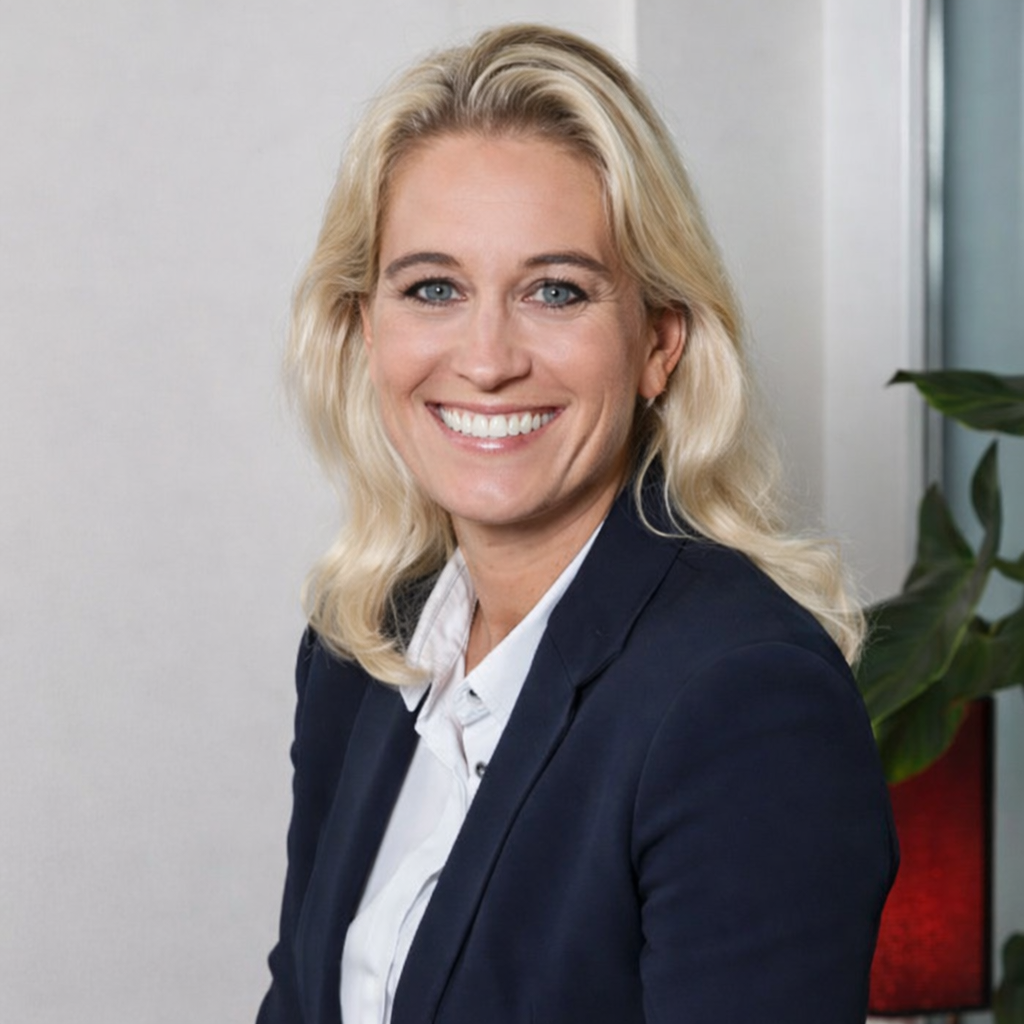 Lächelnde Frau in formeller Kleidung vor neutralem Hintergrund.