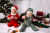 Zwei Babys in Weihnachtskostümen vor einem Weihnachtsbaum mit Geschenken und Dekorationen.