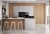 Moderne Küche mit Holz- und Betonoptik, Kücheninsel mit Barhockern, integrierte Backöfen und Mikrowelle, minimalistische Gestaltung.