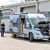 Wohnmobil beim Fahrzeugdiagnose-Service, mit geöffnetem Motorhaube und Technikern, die den Motor überprüfen.